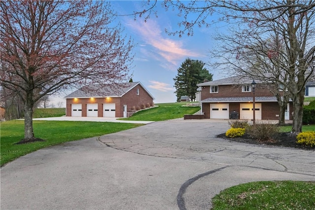 view of front of home with a garage, aphalt driveway, brick siding, and a front lawn