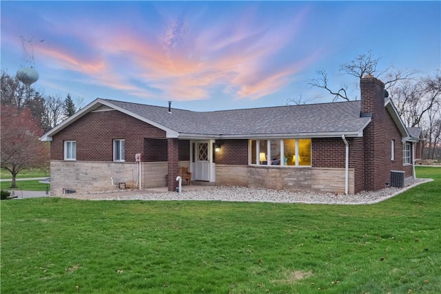 ranch-style home featuring brick siding, a front lawn, a shingled roof, and a chimney