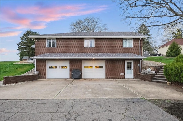 exterior space with concrete driveway, roof with shingles, a garage, and brick siding
