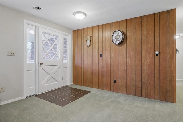 carpeted foyer entrance featuring wooden walls and visible vents