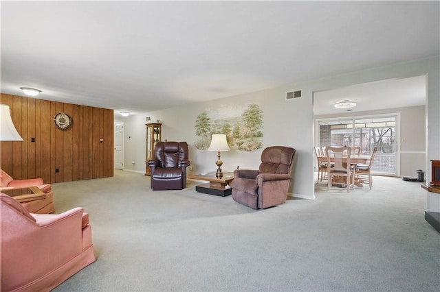 carpeted living room with wood walls and visible vents