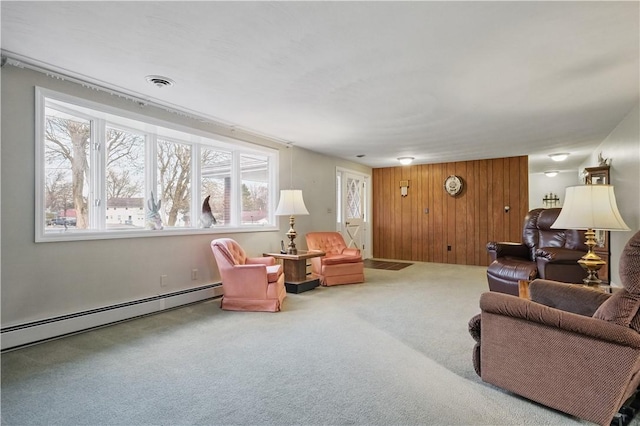 carpeted living room with wooden walls, baseboard heating, and visible vents
