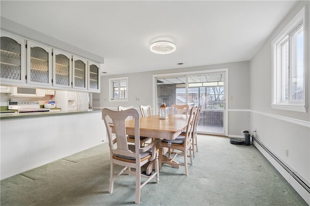 dining space with a baseboard radiator and light colored carpet
