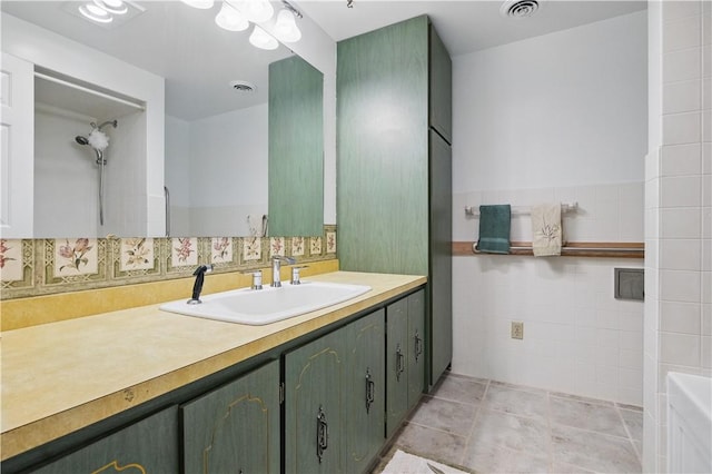 full bathroom with tile walls, vanity, tile patterned flooring, visible vents, and walk in shower