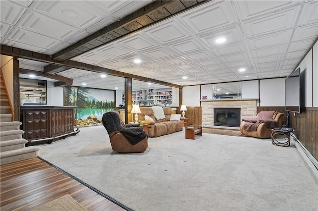 living room with a fireplace, stairway, wooden walls, wainscoting, and an ornate ceiling