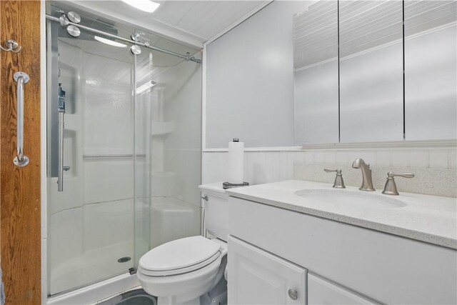 bathroom with toilet, a stall shower, and vanity