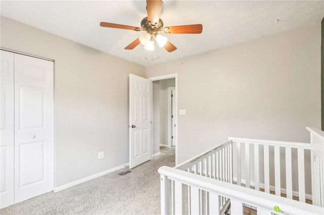 unfurnished bedroom featuring a closet, baseboards, a nursery area, a ceiling fan, and carpet