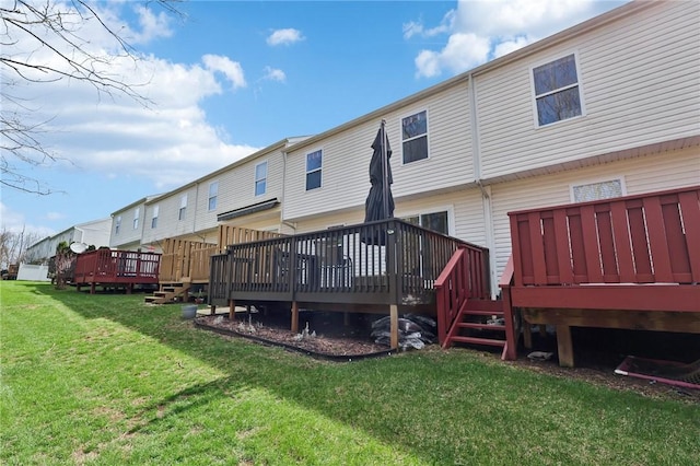 rear view of house featuring a wooden deck and a lawn
