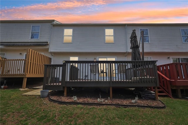 back of house at dusk featuring a yard and a wooden deck