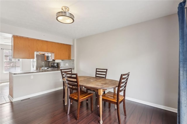 dining space featuring dark wood-style flooring, visible vents, and baseboards