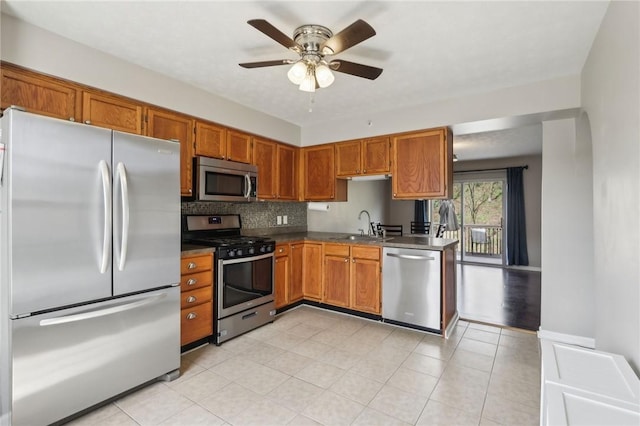 kitchen featuring dark countertops, brown cabinets, a sink, and appliances with stainless steel finishes