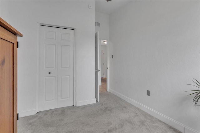 unfurnished bedroom featuring a closet, visible vents, light colored carpet, and baseboards
