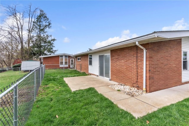 rear view of property with a patio, brick siding, a fenced backyard, and a lawn