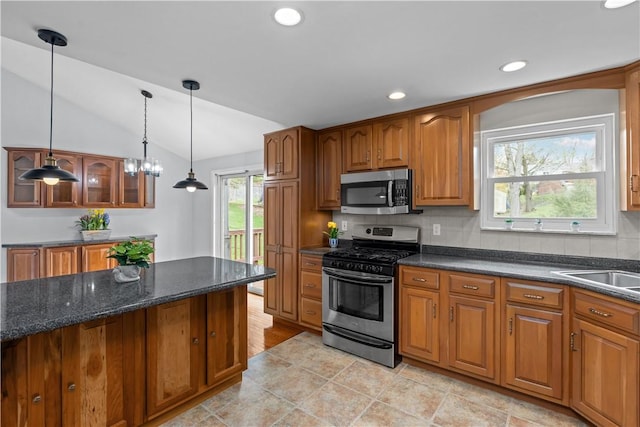 137 Loire Valley Dr, Shaler, PA 15209 - kitchen with hanging light fixtures, brown cabinetry, stainless steel appliances, decorative backsplash, and lofted ceiling