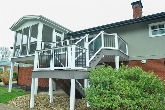view of side of property with stairway, a sunroom, and a chimney
