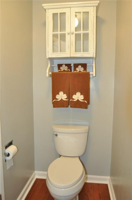bathroom with toilet, baseboards, and wood finished floors