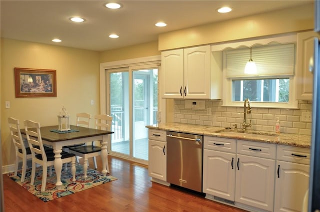 kitchen with white cabinetry, decorative backsplash, stainless steel dishwasher, a sink, and wood finished floors