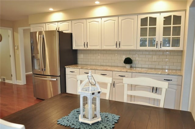 kitchen with white cabinets, tasteful backsplash, glass insert cabinets, and stainless steel fridge
