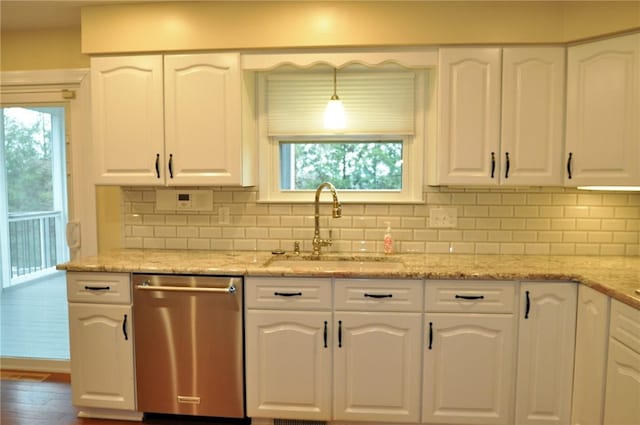 kitchen with a healthy amount of sunlight, stainless steel dishwasher, a sink, and white cabinetry