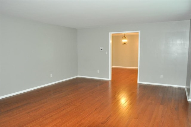 unfurnished room with hardwood / wood-style flooring and baseboards