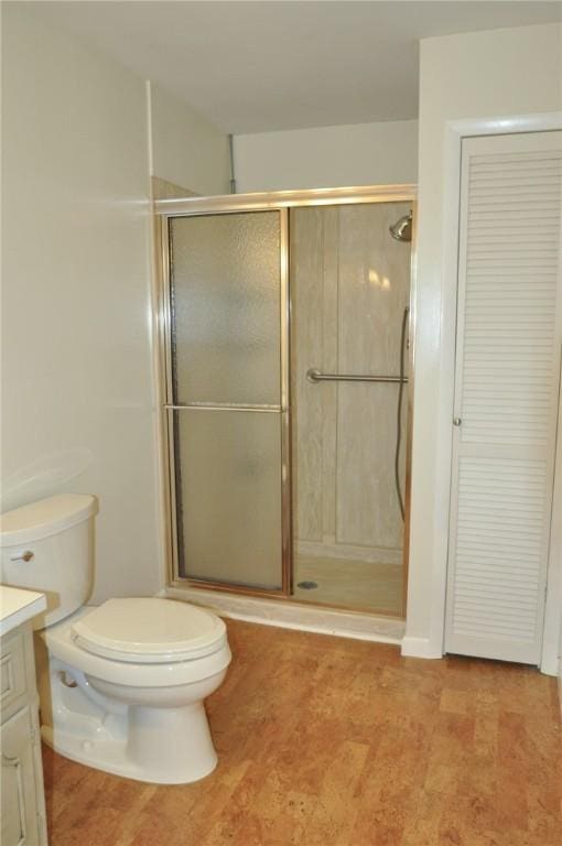 bathroom featuring toilet, a stall shower, and vanity