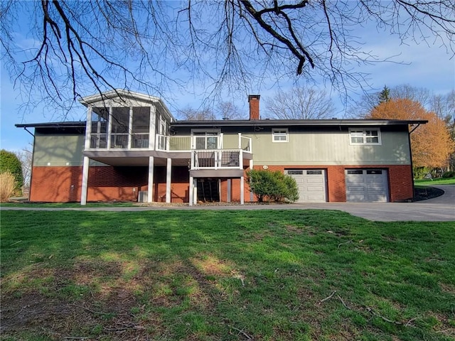 back of house featuring a sunroom, brick siding, a chimney, and an attached garage
