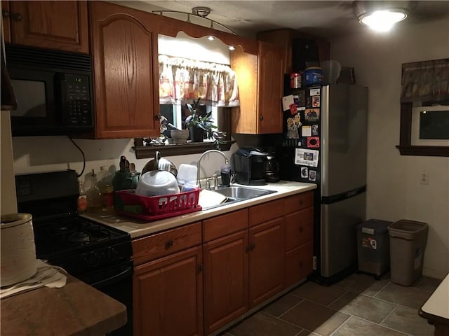 856 School St, Clairton, PA 15025 - kitchen featuring light tile patterned floors, a sink, light countertops, brown cabinets, and black appliances