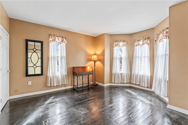 living area with a wealth of natural light, hardwood / wood-style flooring, and baseboards