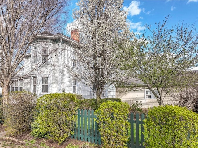 view of home's exterior featuring fence and a chimney