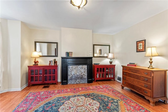 sitting room featuring wood finished floors, a fireplace, and visible vents
