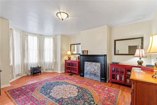 sitting room with a fireplace, baseboards, and wood finished floors