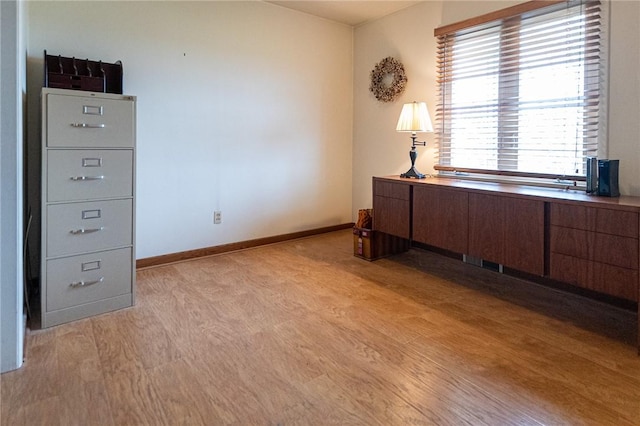 unfurnished office featuring light wood finished floors and baseboards