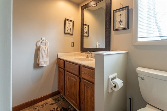 half bath featuring vanity, baseboards, and toilet