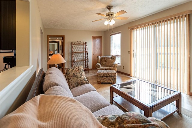 living area featuring ceiling fan, baseboards, and a textured ceiling