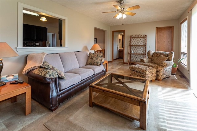 living area featuring ceiling fan and a textured ceiling