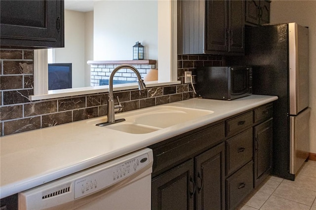 kitchen with white dishwasher, a sink, light countertops, backsplash, and light tile patterned flooring