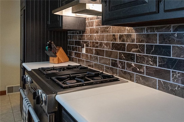 kitchen featuring backsplash, extractor fan, visible vents, and dark cabinetry