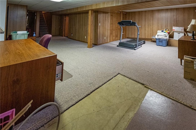 workout area featuring wooden walls, carpet floors, and a drop ceiling