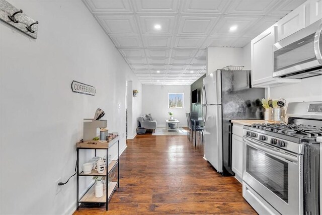 329 Downing St, Polish Hill, PA 15219 - kitchen with white cabinetry, appliances with stainless steel finishes, baseboards, dark wood-style floors, and an ornate ceiling