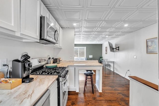 329 Downing St, Polish Hill, PA 15219 - kitchen featuring white cabinets, light stone countertops, dark wood-type flooring, an ornate ceiling, and appliances with stainless steel finishes
