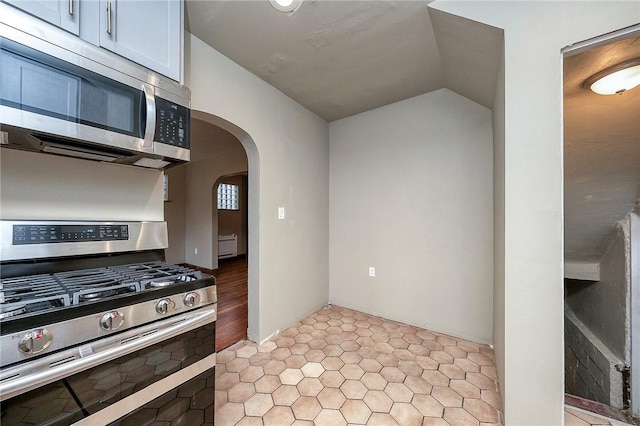 kitchen featuring arched walkways, lofted ceiling, and appliances with stainless steel finishes