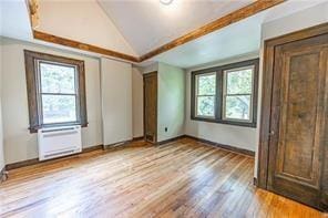 interior space featuring wood finished floors, baseboards, lofted ceiling, and a wealth of natural light