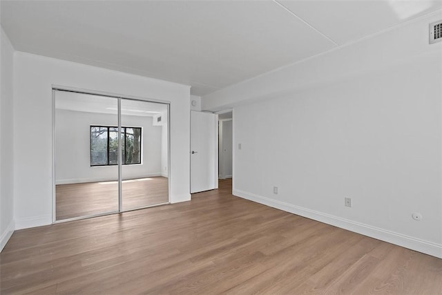 unfurnished bedroom featuring visible vents, baseboards, light wood-type flooring, and a closet