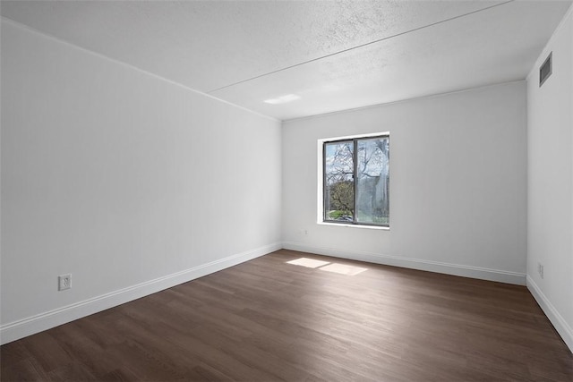 unfurnished room featuring dark wood-style flooring, visible vents, baseboards, and a textured ceiling