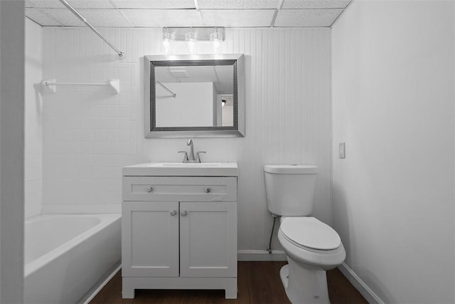 bathroom featuring baseboards, toilet, a paneled ceiling, vanity, and wood finished floors