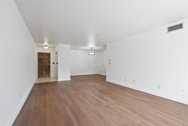 unfurnished room with visible vents, baseboards, and wood finished floors
