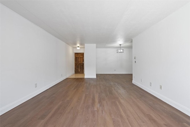 unfurnished living room with baseboards and wood finished floors