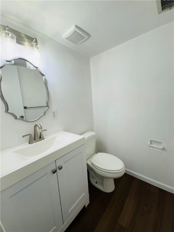 bathroom featuring vanity, visible vents, toilet, and wood finished floors