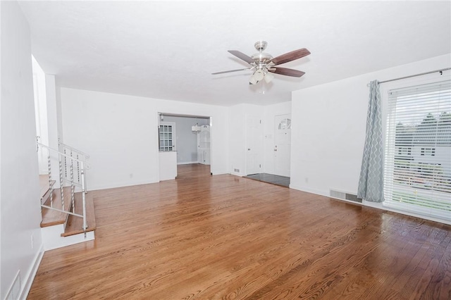 unfurnished living room featuring visible vents, ceiling fan, wood finished floors, and stairs