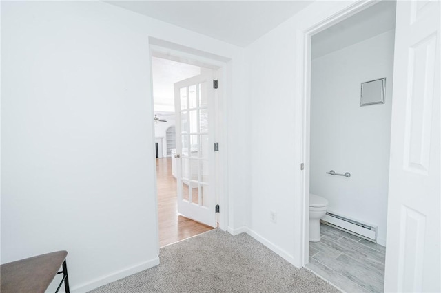 corridor with carpet flooring, a baseboard radiator, and baseboards